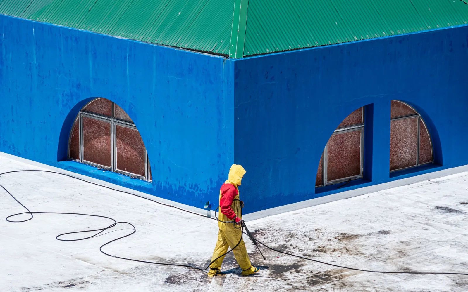 Technician soft washing a residential roof in Eugene, Oregon at low pressure